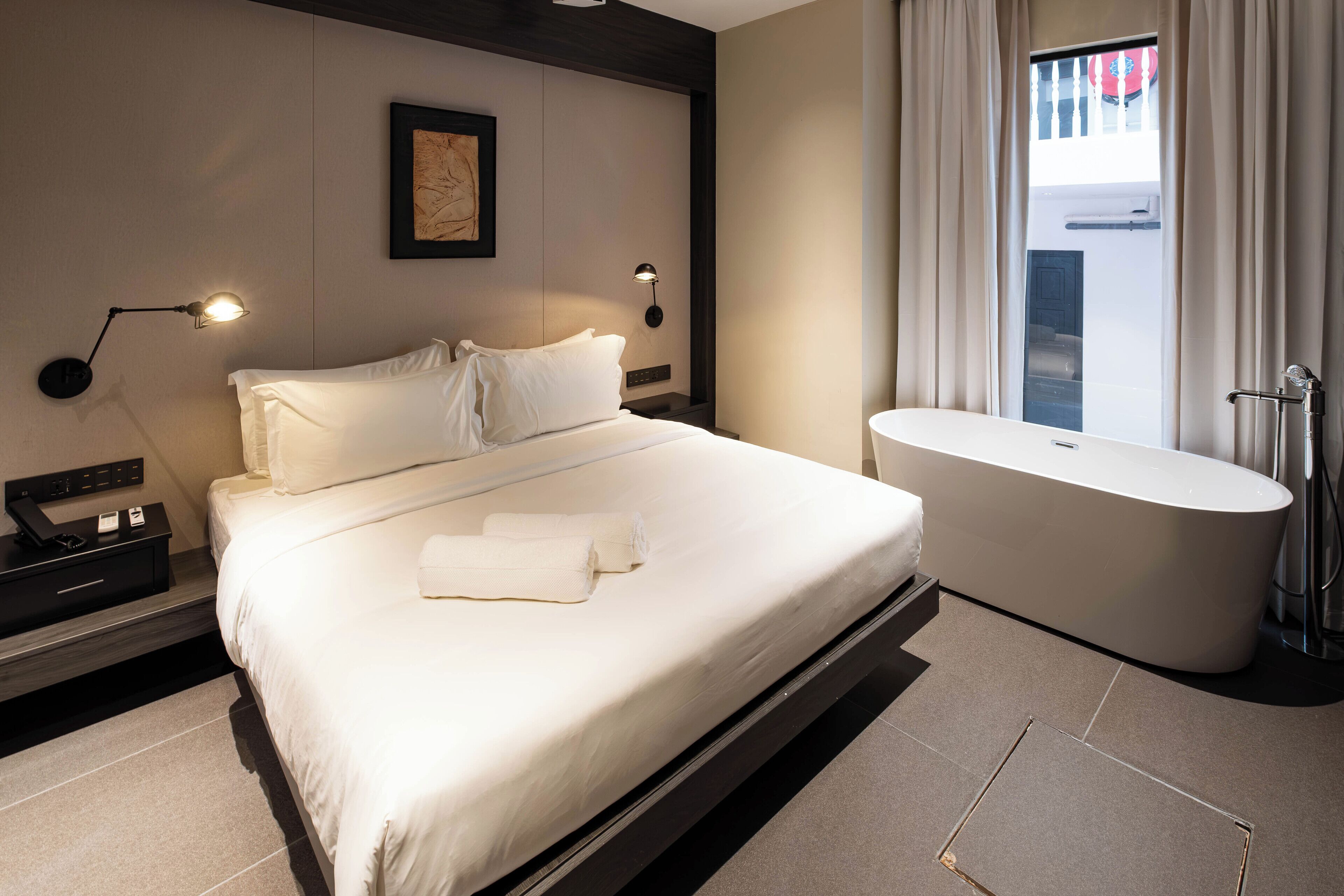 Ett modernt hotellrum med en stor säng, ett separat badrum och utsikt över omgivningarna.