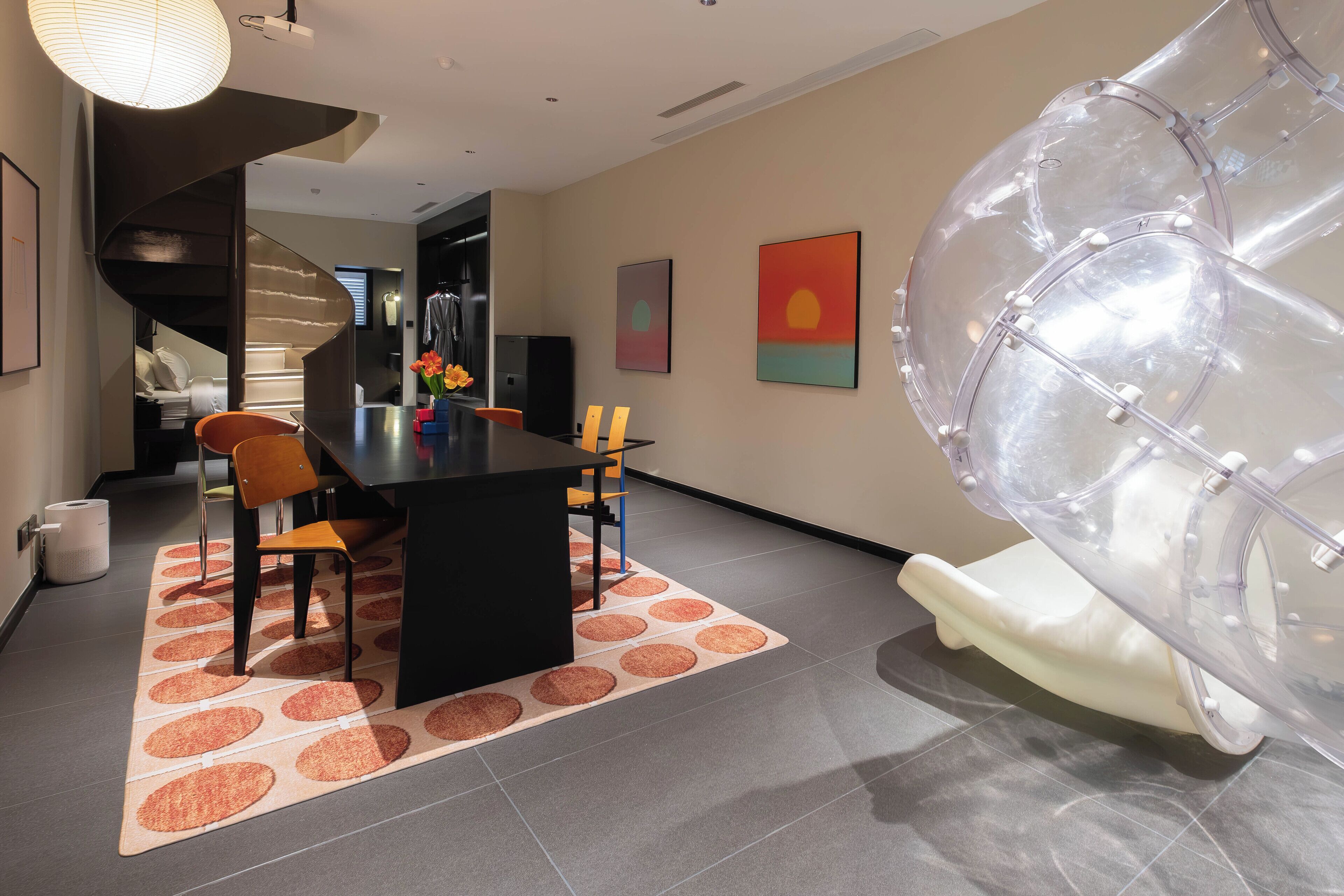 A modern kitchen with a black countertop, a dining area with a table and chairs, and a unique transparent object on the floor.