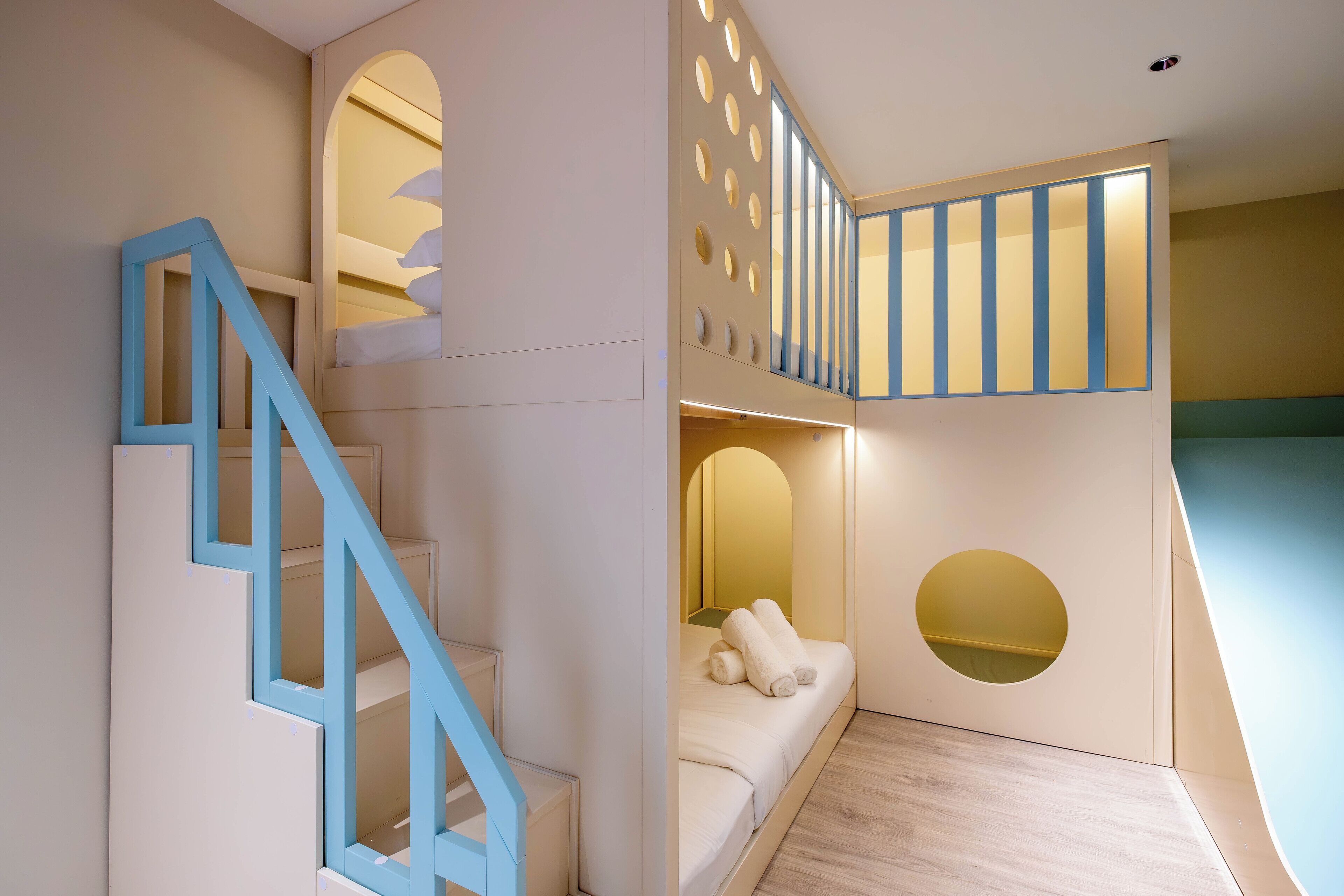 A modern interior with a staircase, a bunk bed, and a small seating area.