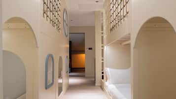 A corridor with bunk beds on either side, wooden flooring, and a neutral color scheme.