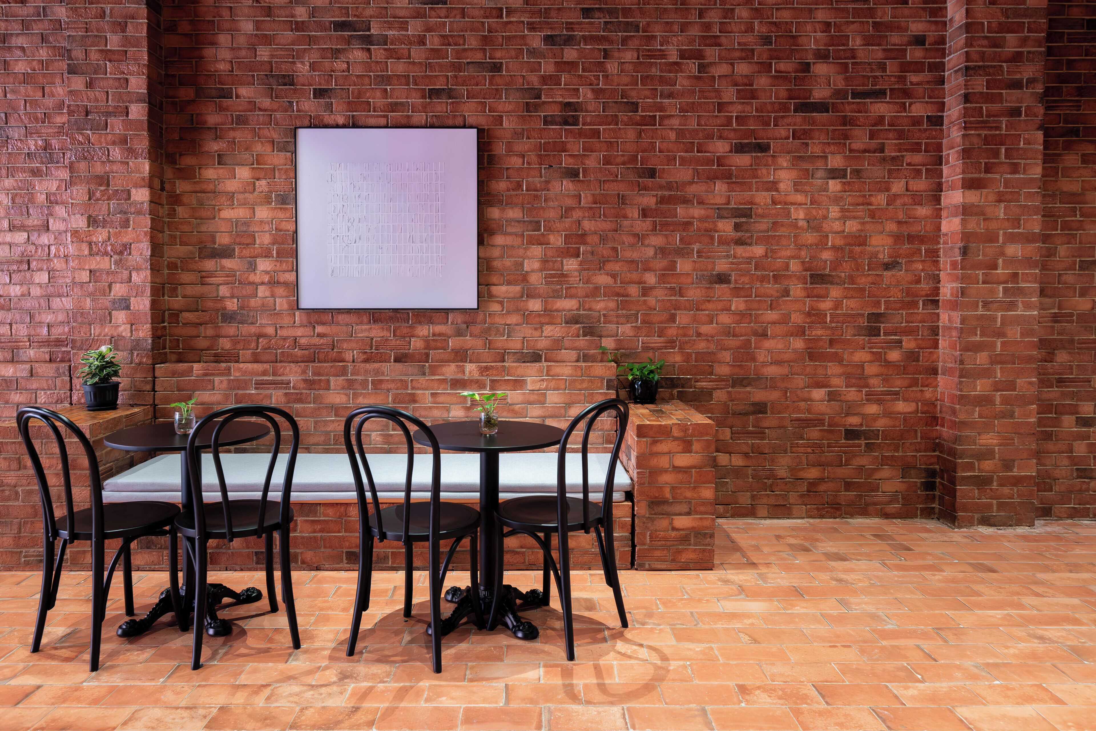 A brick wall with a whiteboard, a round table with four chairs, and a bench.