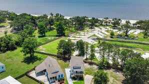 An aerial view of a residential area with houses, a beach, and a water body. - Seaside Serenity Boutique Home (Gulfport)