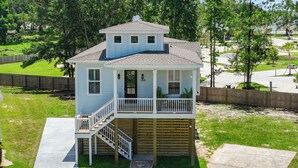 A two-story house with a balcony, a front porch, and a staircase leading to the second floor. - Seaside Serenity Boutique Home (Gulfport)