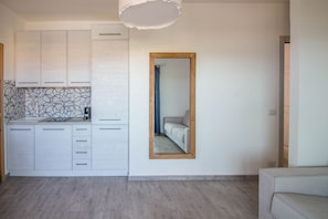 Eine moderne Küche mit weißen Schränken, einem spiegelnden Wandbild mit Holzrahmen und einer gemusterten Spritzschutzwand.