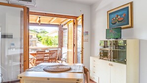 A room with a wooden table, chairs, a cabinet, and a painting on the wall.