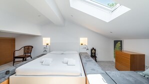 A modern bedroom with a skylight, a bed, bedside tables, a chair, a dresser, and a clock. - GuestReady - Relaxing duplex near Parque da Cidade (Senhora da Hora)