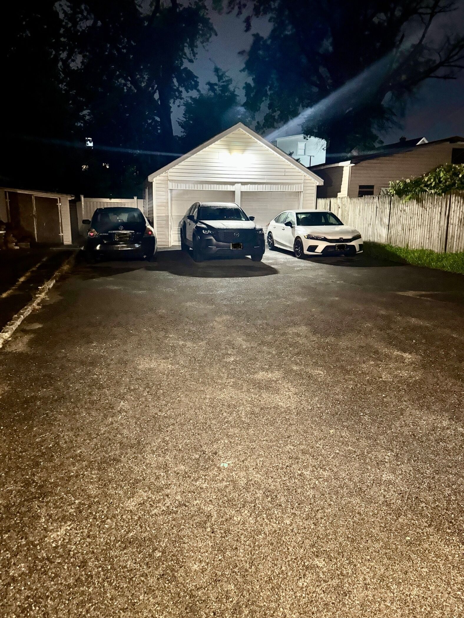Un garaje con tres coches estacionados frente a él.