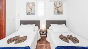 A hotel room with two beds, a nightstand with a lamp, and artwork on the walls. - Villa Canada (Tías)