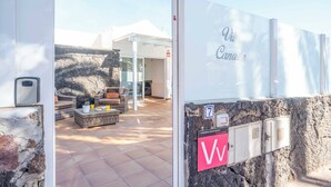 A villa entrance with a stone wall, a glass door, and a sign reading "Villa Canara." - Villa Canada (Tías)