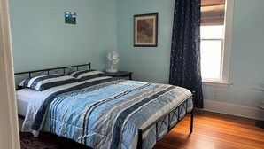 A bedroom with a bed, a bedside table with a fan, a window with curtains, and a wall with a picture. - A sweetheart home
3-bedroom vacation home, 6 minutes to Rivers Casino & Resort (Schenectady)
