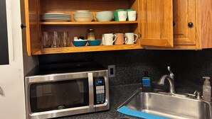 A kitchen with a microwave, sink, and wooden shelves holding dishes and glasses. - A sweetheart home
3-bedroom vacation home, 6 minutes to Rivers Casino & Resort (Schenectady)