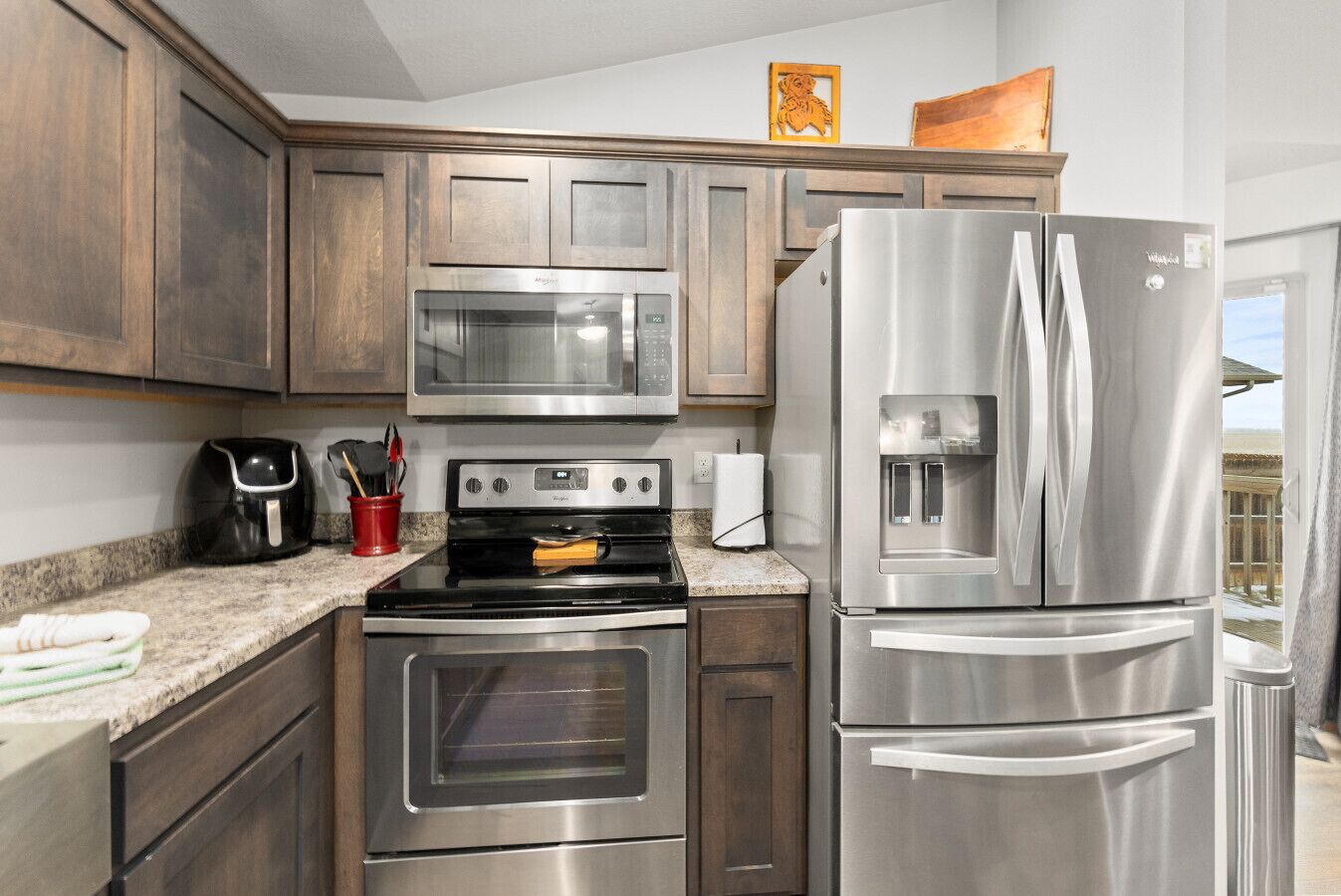 A modern kitchen with stainless steel appliances, wooden cabinets, and granite countertops.