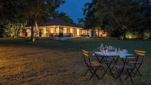 An outdoor dining area with a table and chairs set up on a grassy lawn, with a building in the background. - 4 Bedroom Golf Lake Front Villa in Casa de Campo (La Romana)