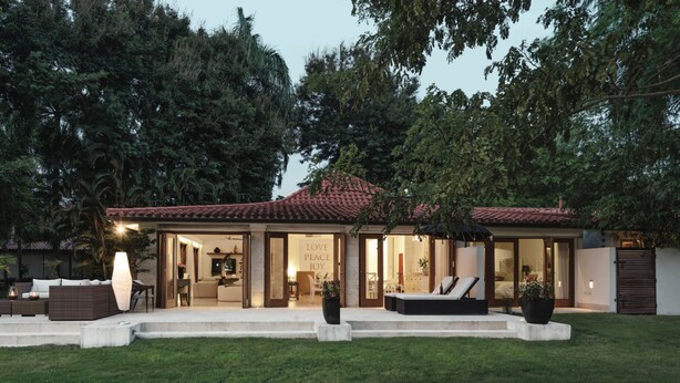 A modern house with a patio, outdoor seating, and a large garden. - 4 Bedroom Golf Lake Front Villa in Casa de Campo (La Romana)