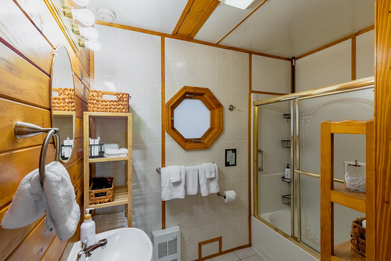 A bathroom with a wooden vanity, a shower with a glass door, and a towel rack.