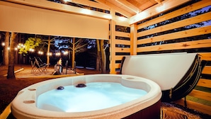 Un bain à remous doté d’une terrasse en bois et d’un espace salon abrité.
