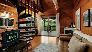 L’intérieur d’un chalet en bois comprend un salon, un balcon, une cheminée et un téléviseur avec accès à Hulu.
