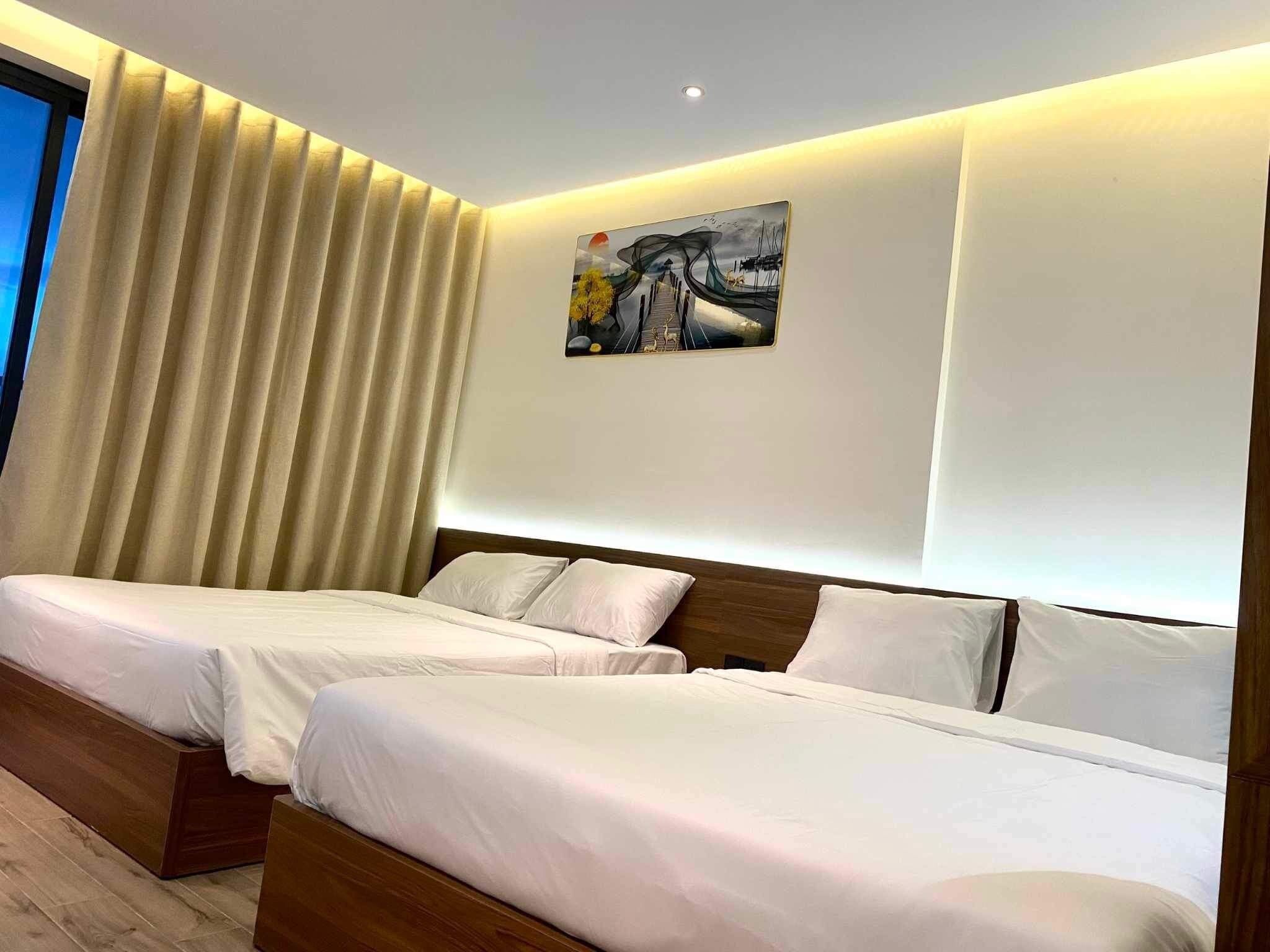 A hotel room with two beds, a large window with curtains, and a painting on the wall.