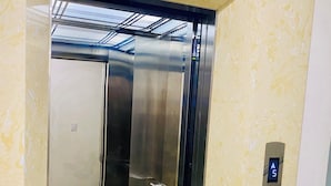 An elevator with a metallic interior and a patterned floor. - Gem Hostel (Hai Phong)