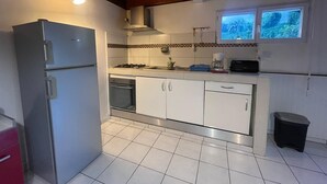 Eine Küche mit weißen Schränken, einem Side-by-Side-Kühlschrank, einem Gasherd und einem Fenster mit Blick auf Grünflächen.