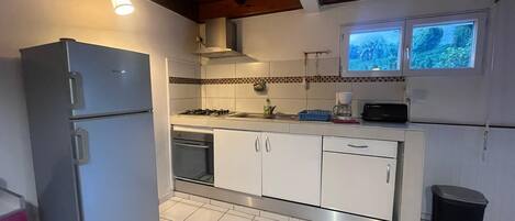 A kitchen with white cabinets, a double-door refrigerator, a gas stove, and a window with a view of greenery.