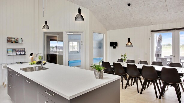 Cocina moderna con una isla grande, comedor con sillas y vistas al exterior.