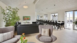 Una habitación espaciosa con diseño moderno, que cuenta con un amplio comedor, asientos cómodos y un ventanal con vistas.