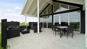 Un patio techado al aire libre con una mesa de comedor y sillas, un sofá y una pequeña mesa auxiliar.