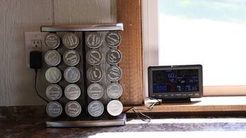 A kitchen with a coffee maker and a digital clock on the counter.