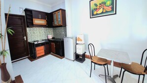 Une cuisine de taille réduite, dotée de meubles de rangement sombres, d’un crédence carrelée, d’un réfrigérateur, d’un four à micro-ondes et d’une table à manger avec des chaises.