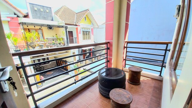 Un balcon doté d’un sol carrelé, d’une rambarde en métal et de deux tabourets décoratifs.
