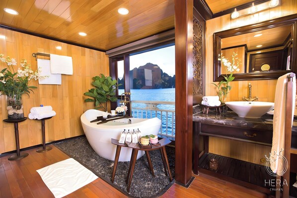 Un baño lujoso con una bañera grande, un tocador con lavamanos y vistas al agua.