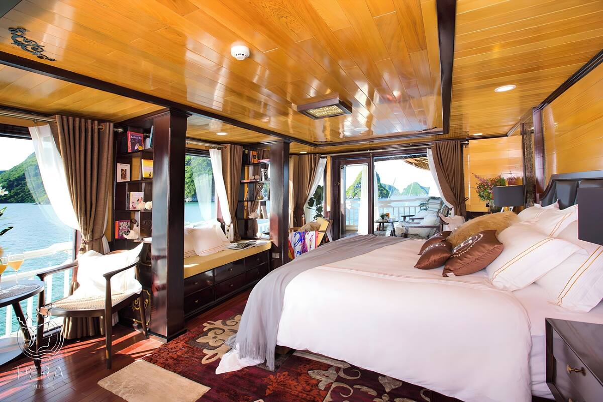 Eine luxuriöse Hütte mit einem großen Bett, einer Sitzecke mit Meerblick und einem Bücherregal.