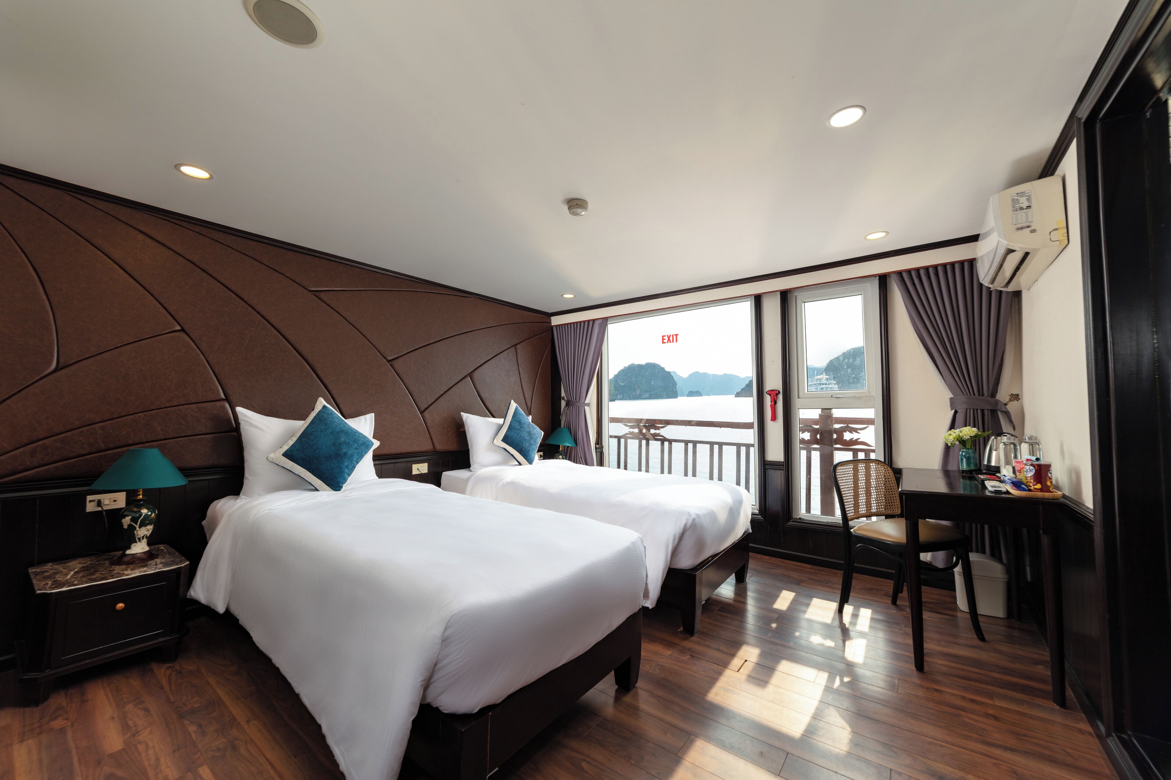 Une chambre d’hôtel avec deux lits, un bureau et vue sur la mer.