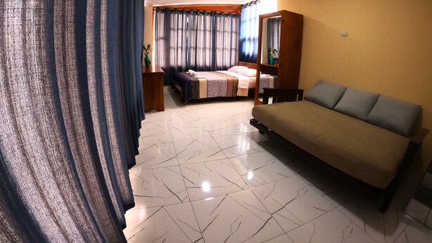 Een hotelkamer met een bank, een bed, een eettafeltje en een spiegel.
