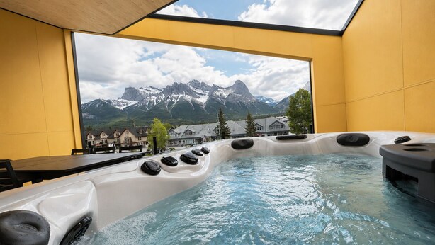 A hot tub with a mountain view, a wooden ceiling, and a yellow wall. - 4 BR with Epic Mountain View, Hot Tub, Garage EV Port, Super High Ceiling (Canmore)
