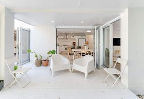 A modern interior with a dining area, white chairs, and potted plants.