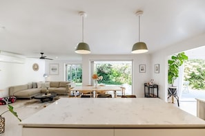 A modern kitchen with a large island, pendant lighting, and a view of the outdoors.