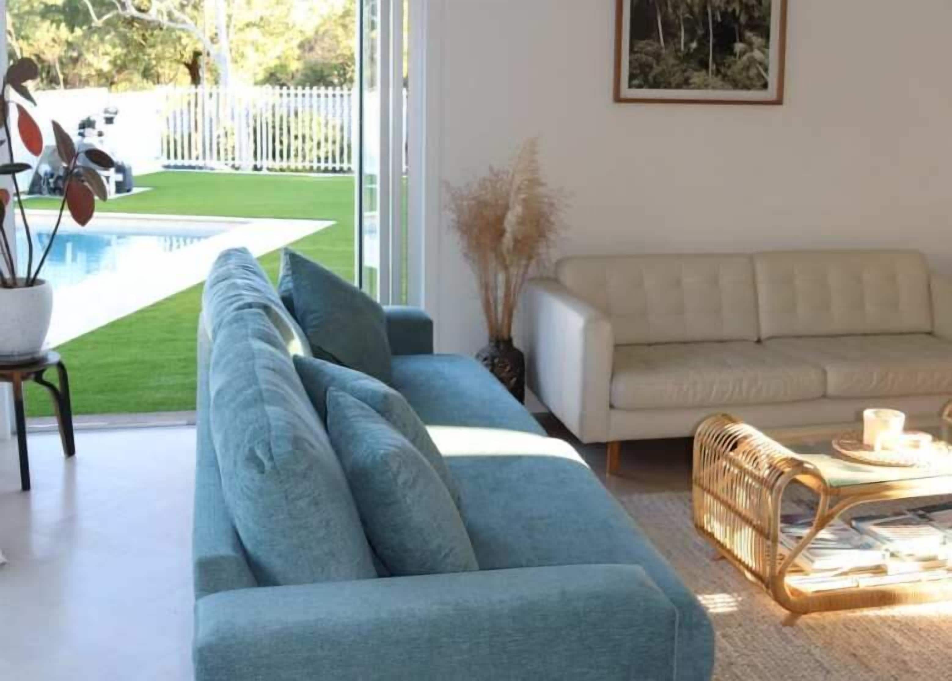 Una sala de estar con un sofá, una mesa de centro y vista a una piscina.