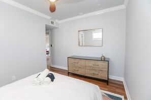 Un dormitorio con una cama, un aparador, un espejo y una puerta que da a otra habitación.
