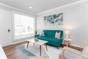 A modern living room with a teal sofa, a white coffee table, and a lamp on a side table.