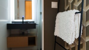 Een badkamer met een handdoekhouder, een witte handdoek, een spiegel en een behang met een patroon.
