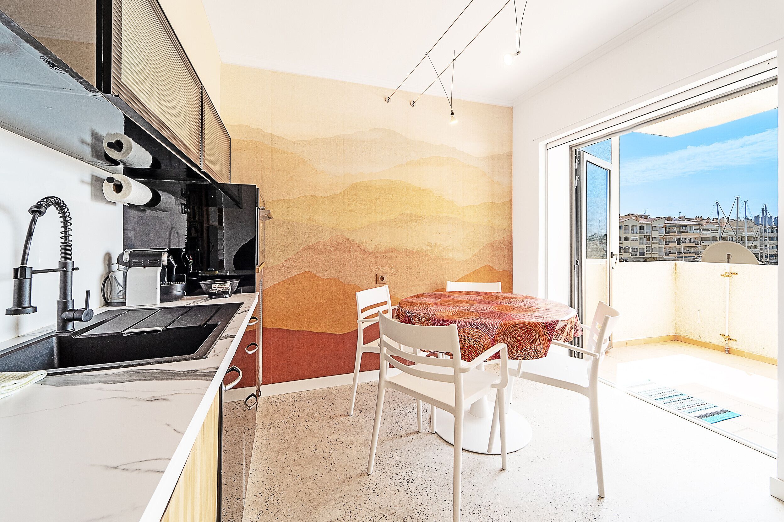 Une cuisine moderne équipée d’un évier, d’une cuisinière et d’un coin repas avec des chaises et une table.
