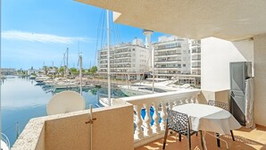 Een balkon met een tafel en stoelen, met uitzicht op een jachthaven met boten en gebouwen.