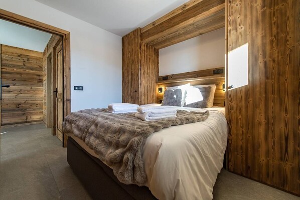 Un dormitorio con cabecera de madera, una cama grande con ropa de cama blanca y un plaid de piel.
