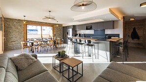 Una cocina moderna con una isla central, comedor con sillas y sala de estar con sofá y mesa de centro.