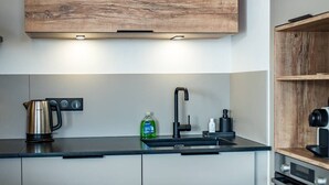 Eine moderne Küche mit einem Holtschrank, einem eingebauten Herd und einer Essecke mit Tisch für zwei Personen.