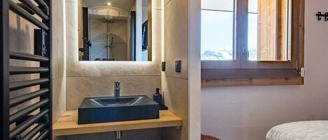 A modern bathroom with a built-in sink, a mirror, and a shower.
