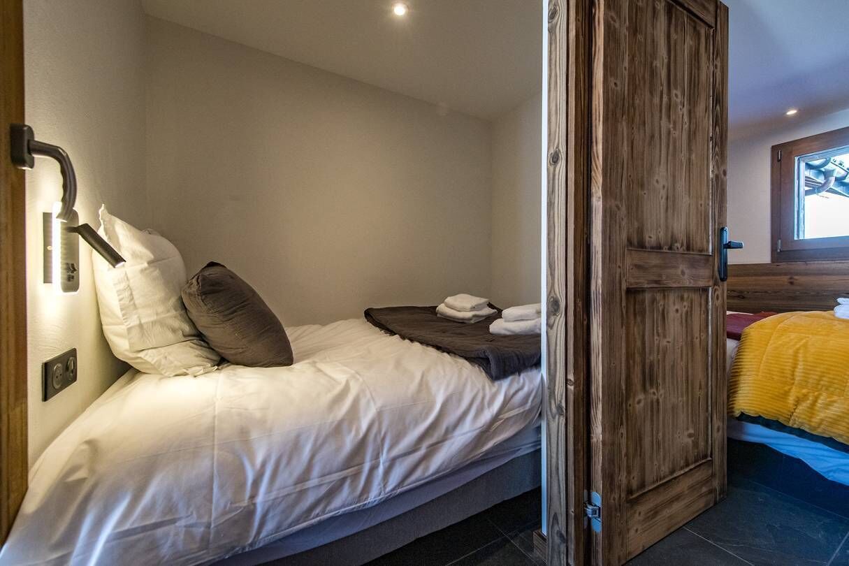 Une chambre avec un lit simple, une porte en bois et une fenêtre donnant sur un paysage agréable.