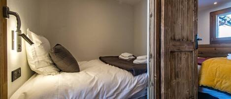 Une chambre avec un lit simple, une porte en bois et une fenêtre donnant sur un paysage agréable.